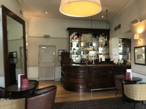 a bar with a glass shelf and chairs