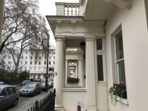 a white building with columns and a fence