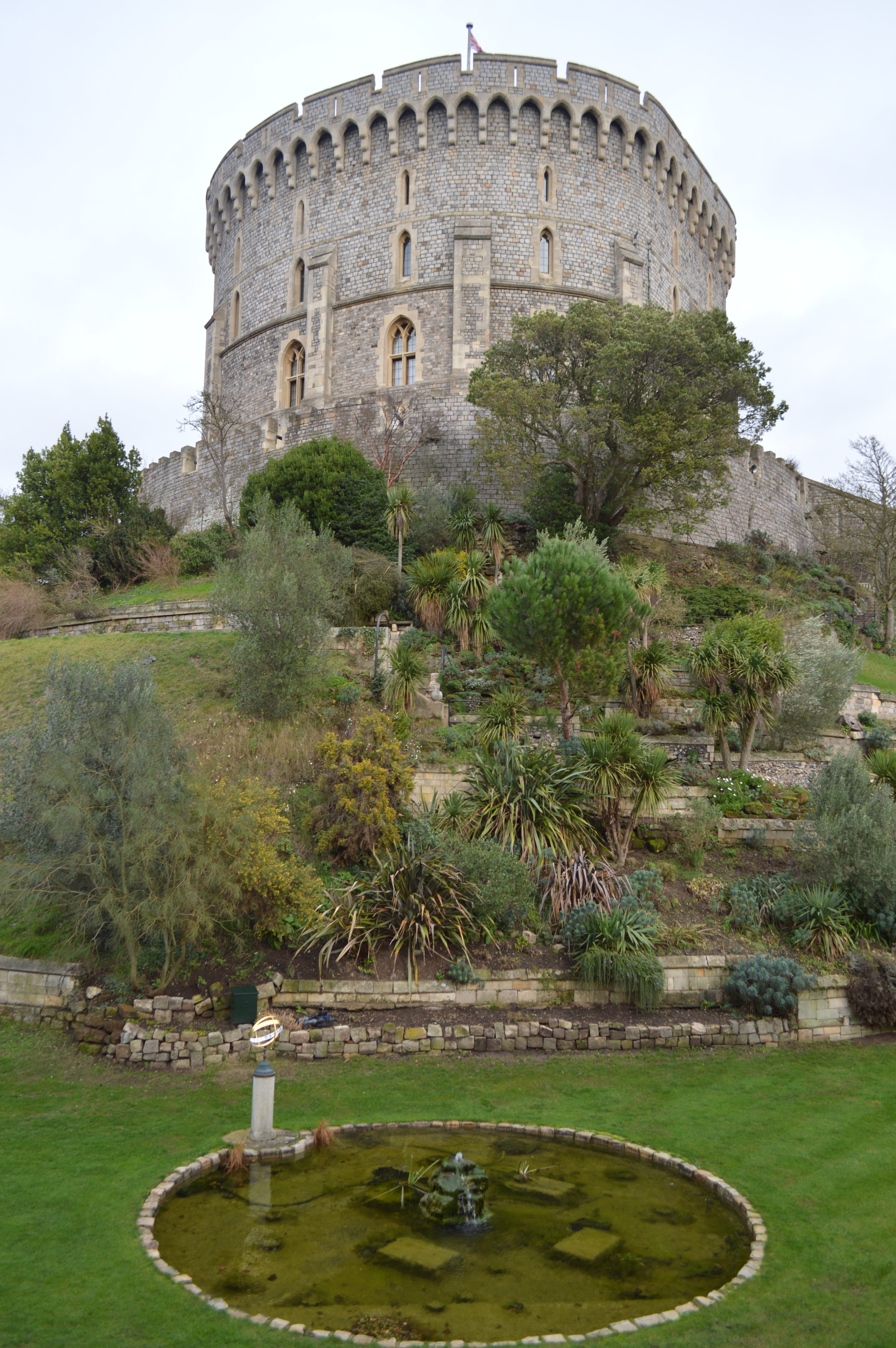 a stone castle with trees and bushes with Windsor Castle in the background