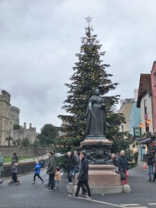 a statue of a woman in a dress with a christmas tree in the background