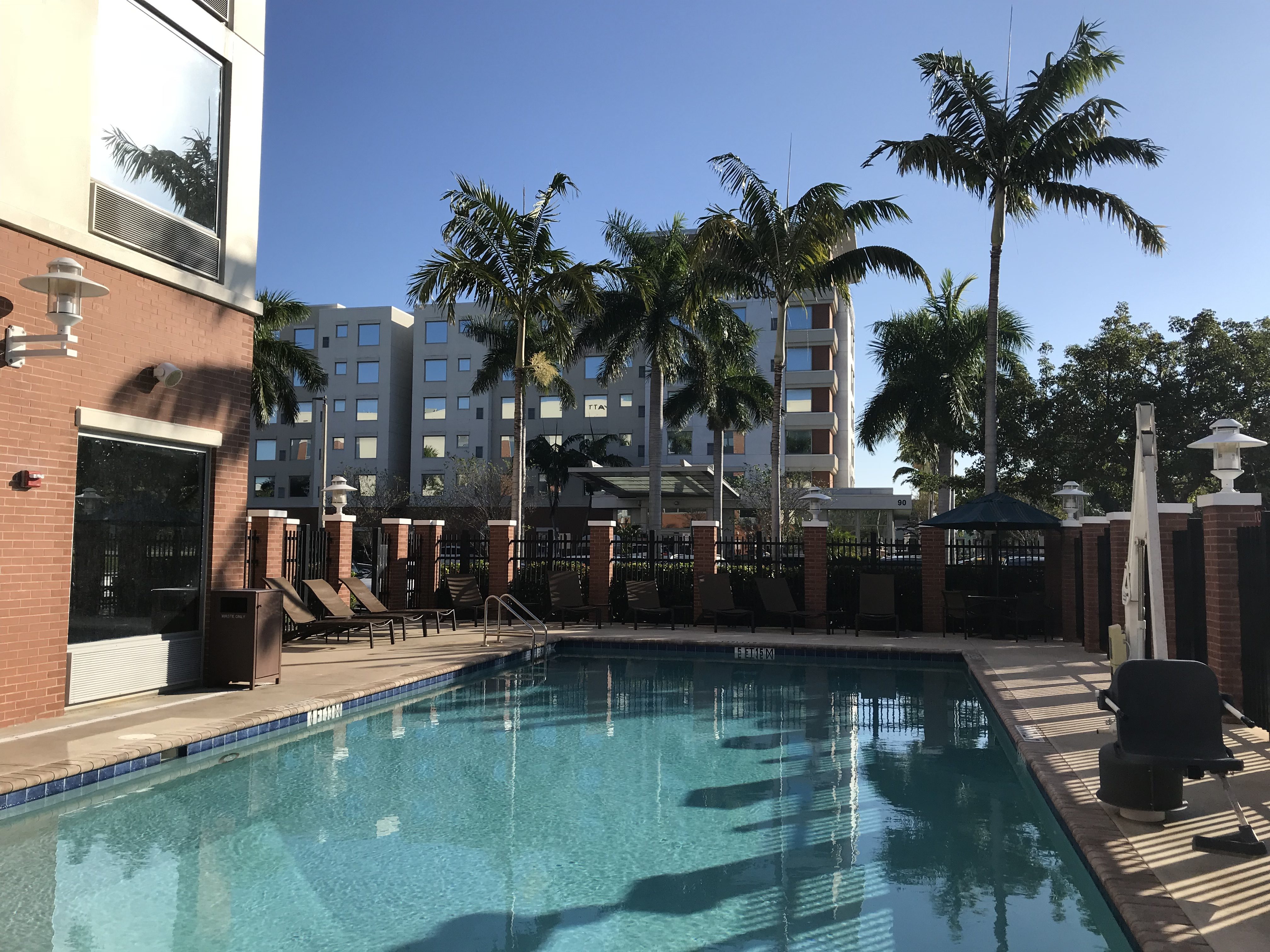 a pool with palm trees and a building in the background