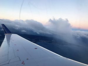 a wing of an airplane flying over clouds