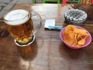 a glass of beer and a bowl of chips on a table