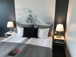 a bed with a black pillow and two white lamps