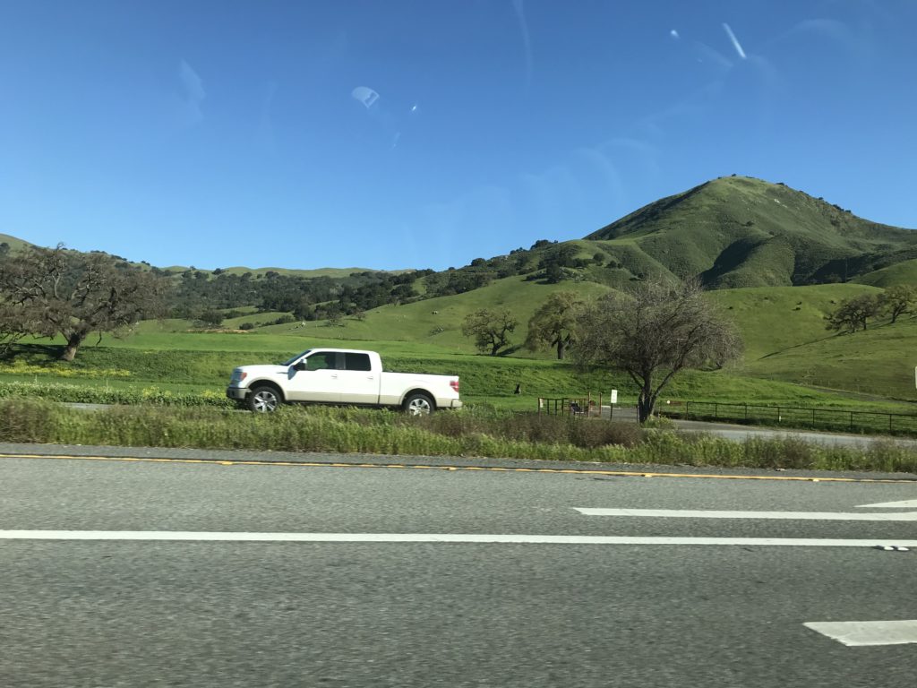a white truck parked on the side of a road with green hills