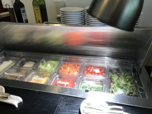 a salad bar with food in plastic containers
