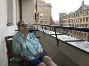 a woman sitting on a balcony drinking from a beer