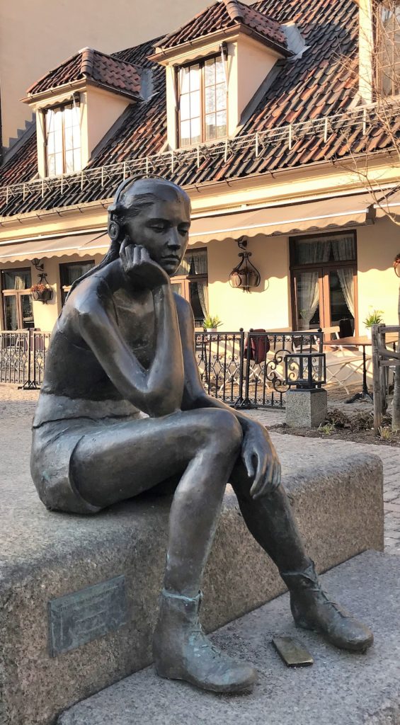 a statue of a woman sitting on a stone bench