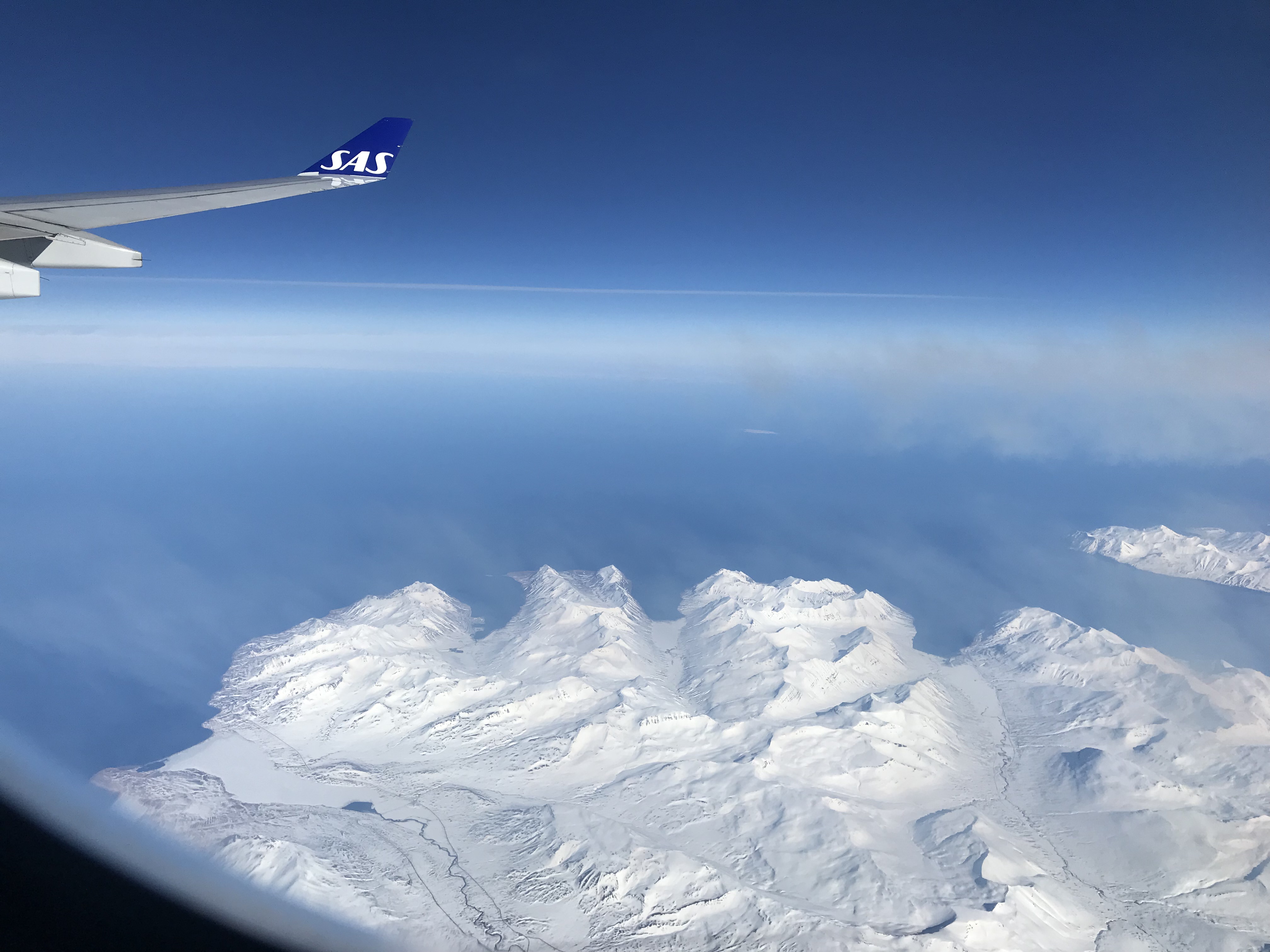 an airplane wing above a snowy mountain range