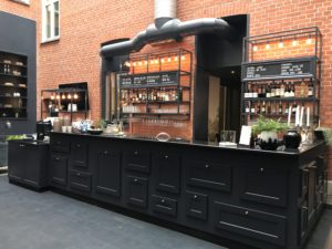 a bar with black cabinets and shelves in front of a brick building