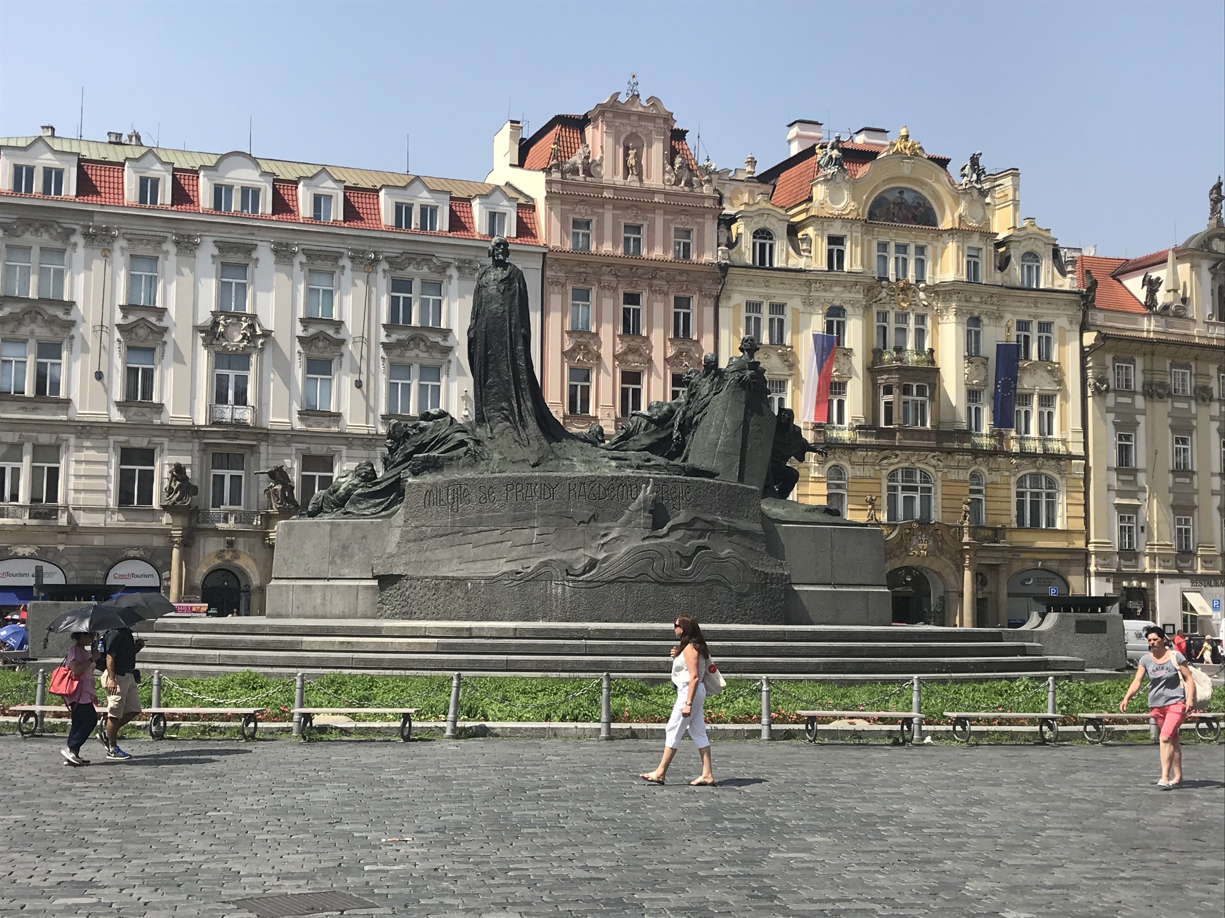 a woman walking in front of a statue in a city