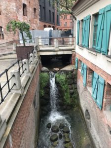 a small waterfall in a small canal between buildings