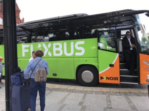 a green and orange bus with people standing next to it