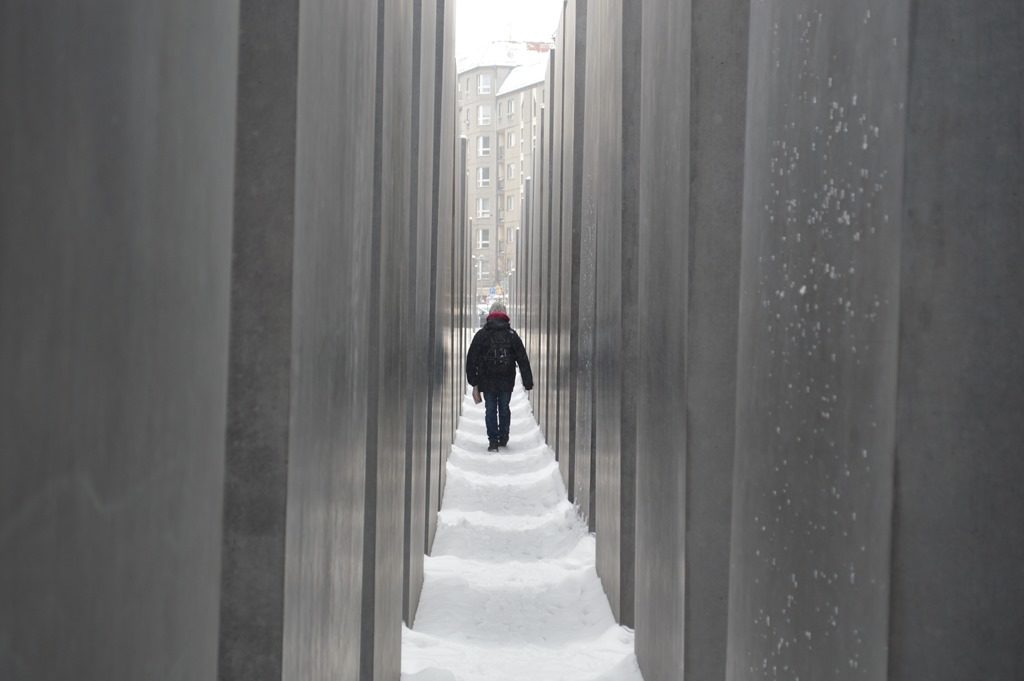 a person walking through a tunnel of tall concrete pillars