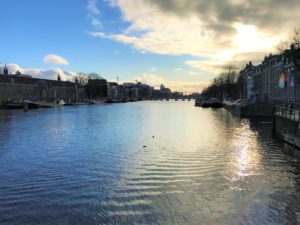 a river with buildings and boats in the background