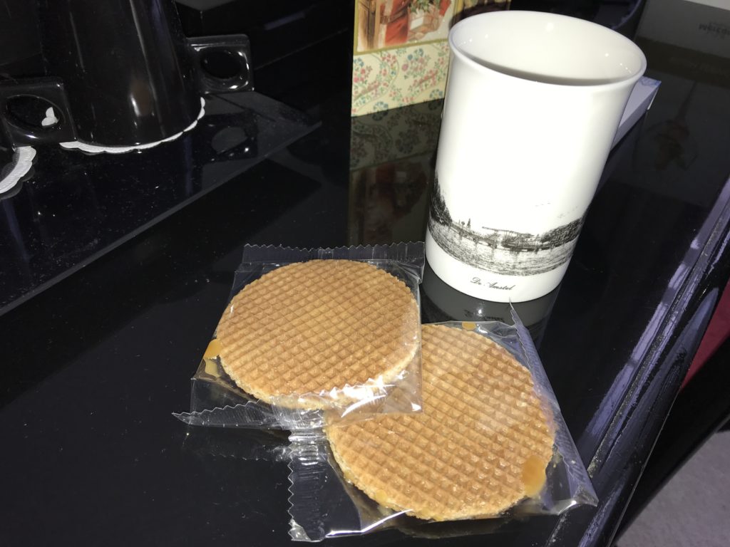 two waffles in plastic wrappers next to a cup