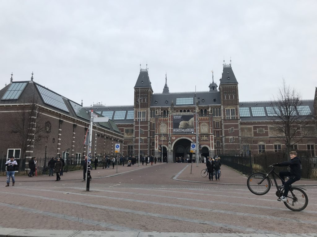 a large brick building with people walking around with Rijksmuseum in the background