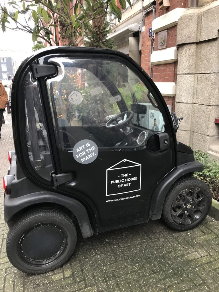 a small black car parked on a brick sidewalk