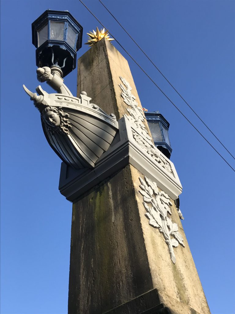 a stone pillar with a lamp post and a ship