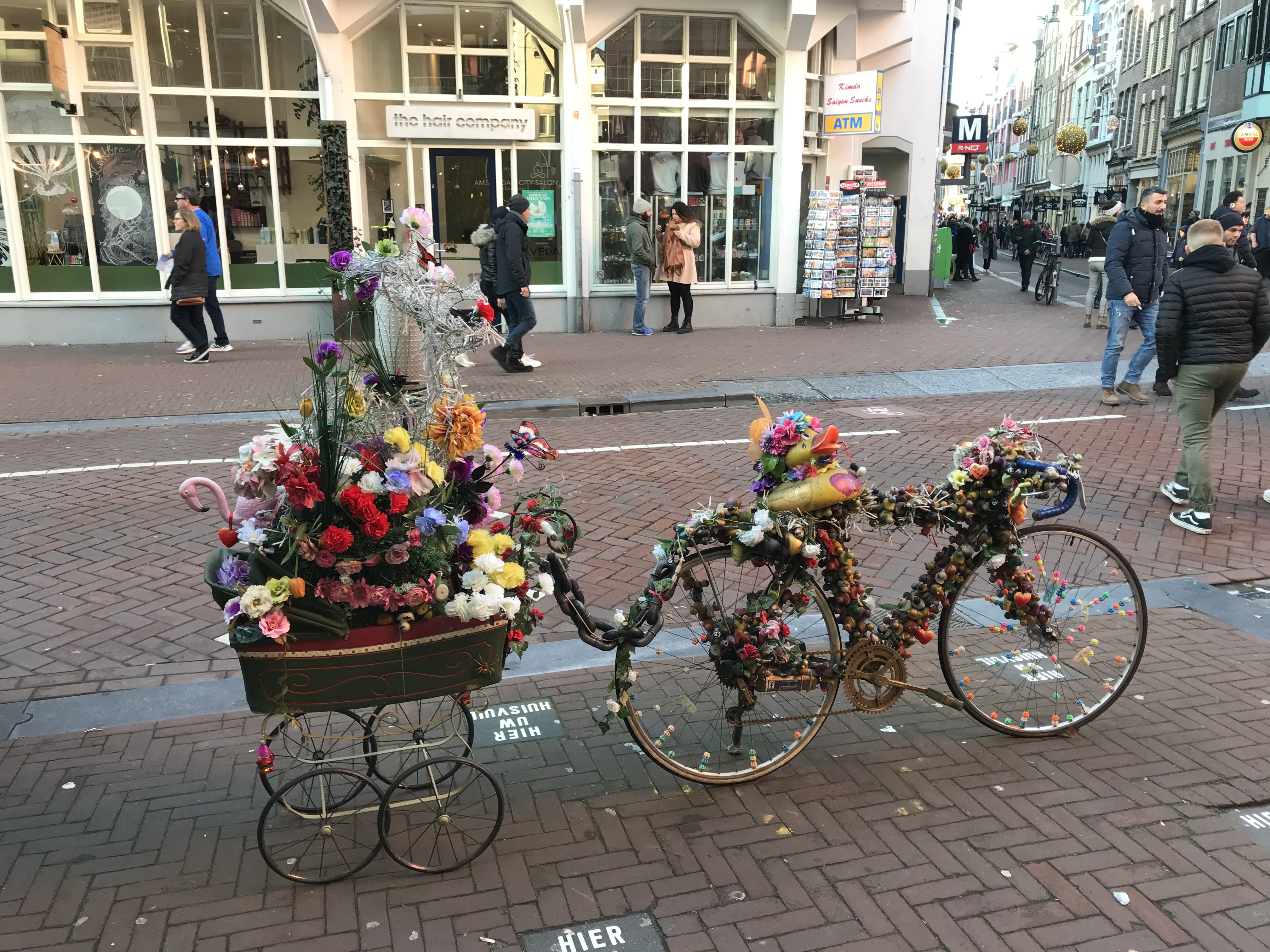 a bicycle with flowers and a cart on the side of the road