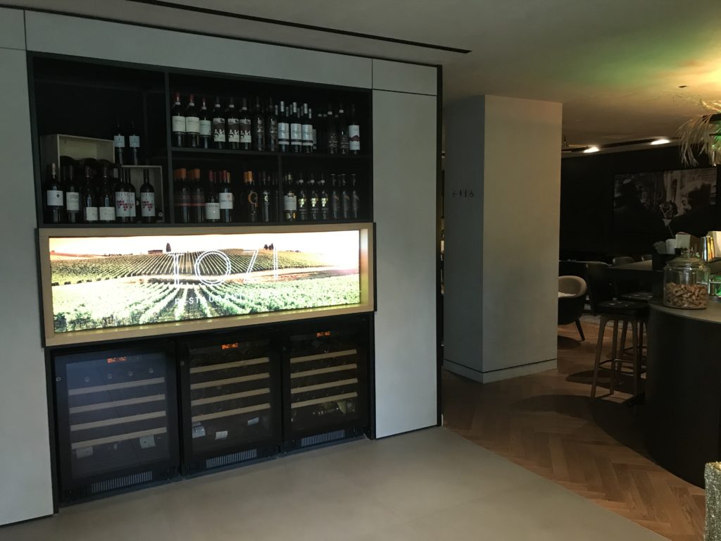 a room with a television and shelves of wine