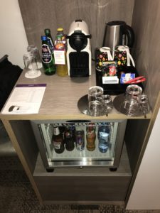 a mini fridge with drinks and coffee cups
