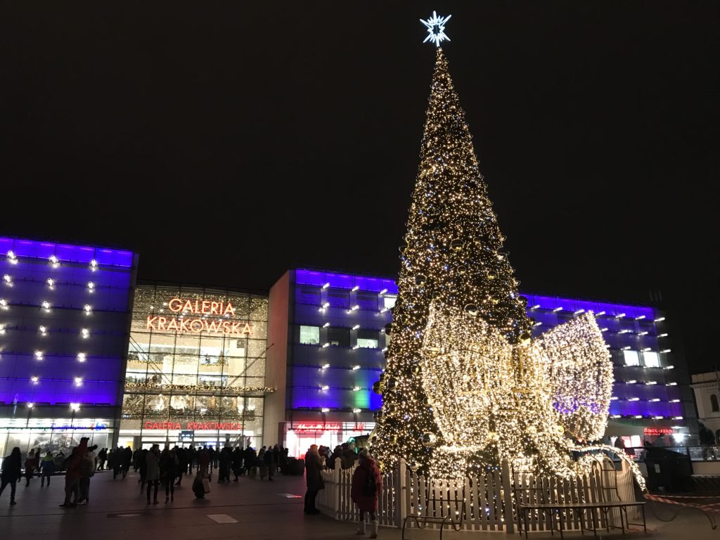a large christmas tree with lights in front of a building