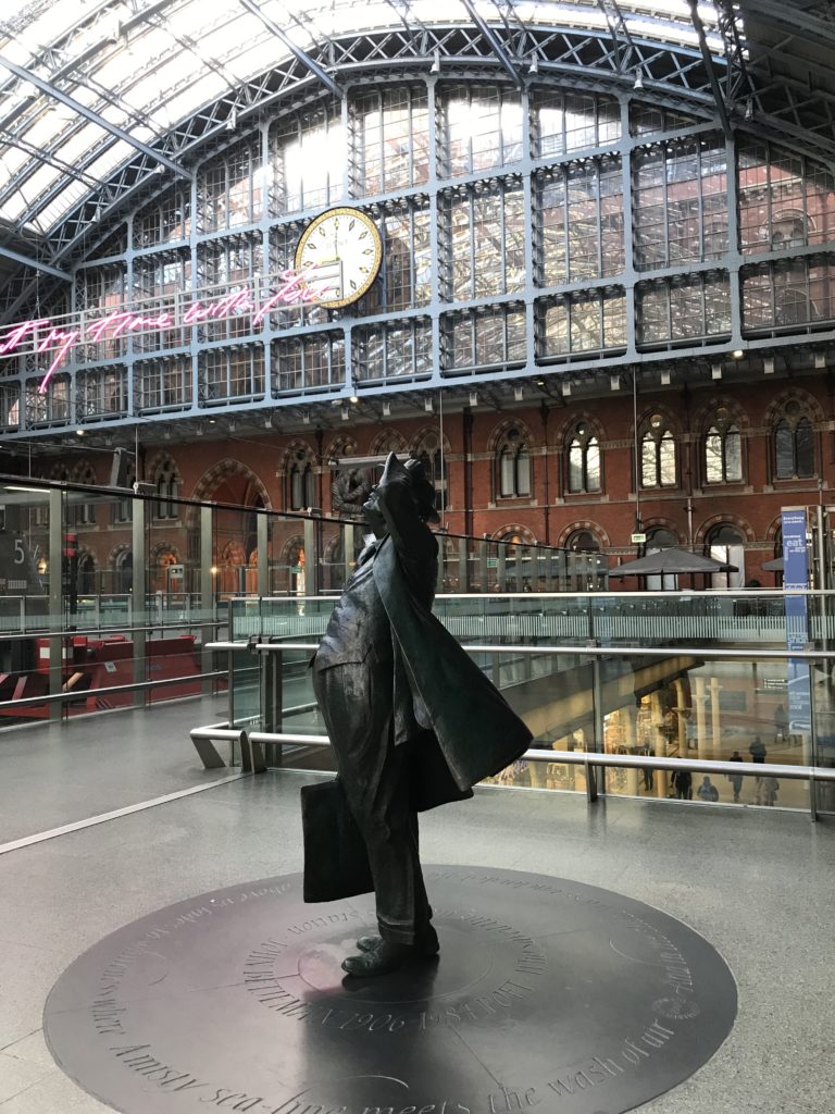 a statue of a man in a suit in a train station
