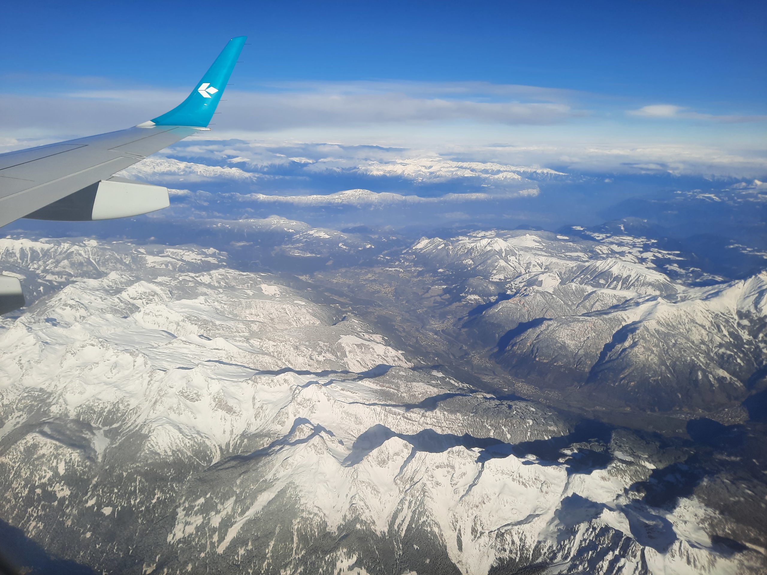 an airplane wing over a snowy mountain range