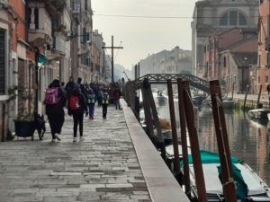 people walking on a sidewalk next to a canal