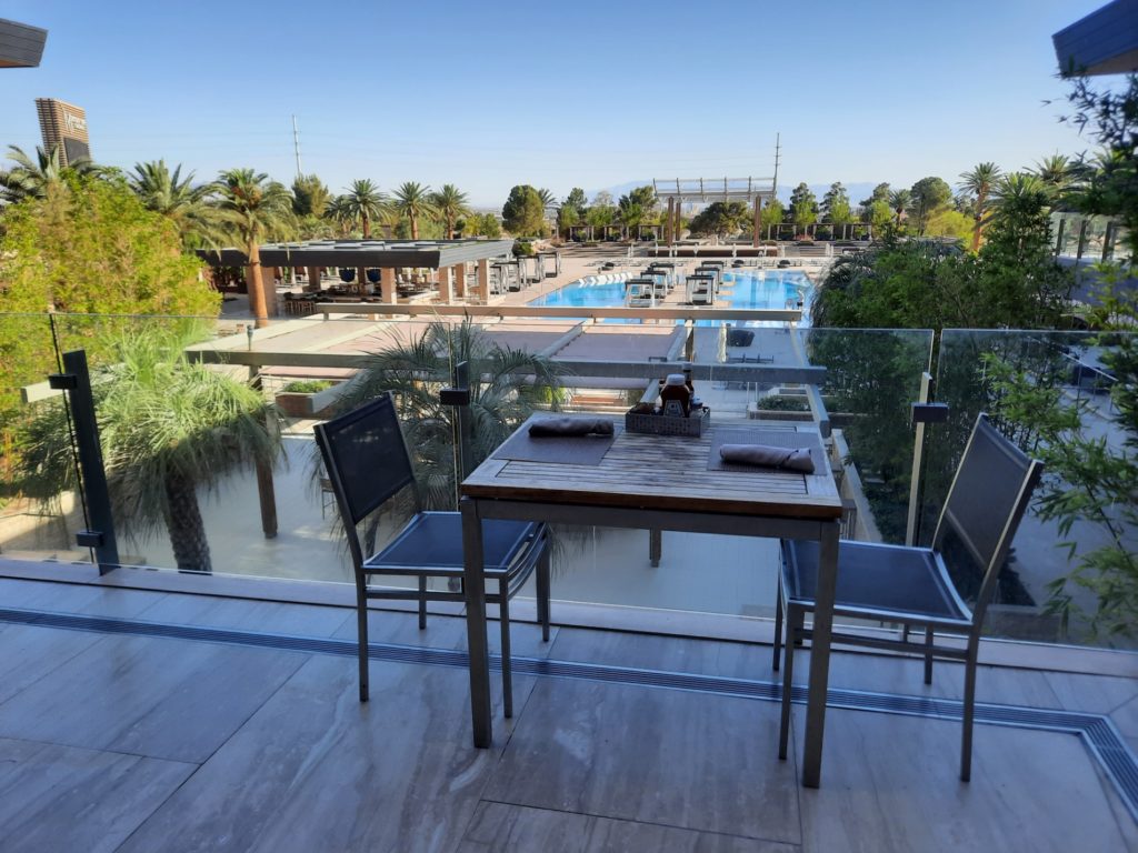 a table and chairs on a balcony overlooking a pool