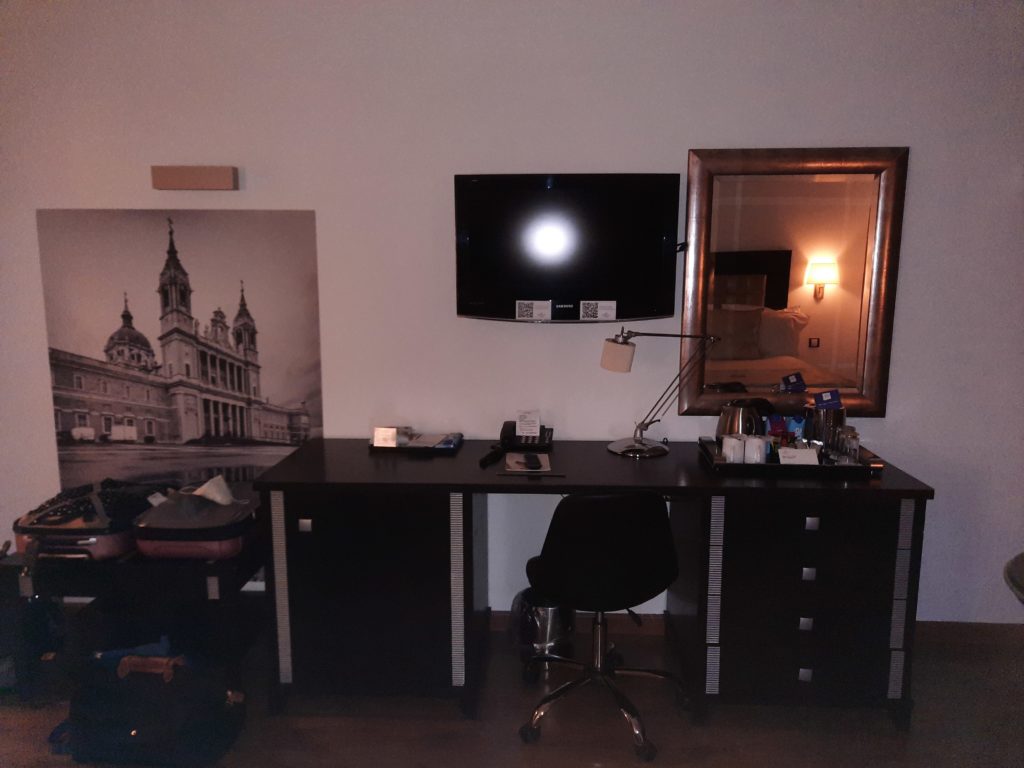 a desk with a mirror and a television on the wall