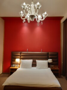 a bed with a chandelier and a red wall