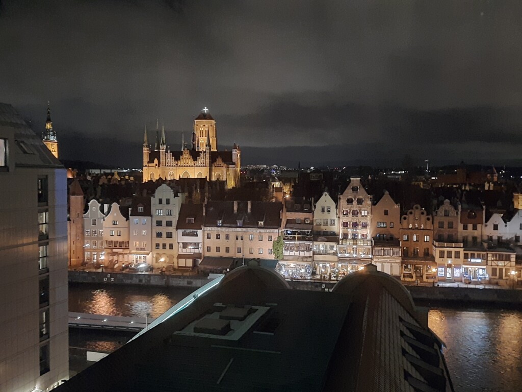 a city at night with a river and a castle