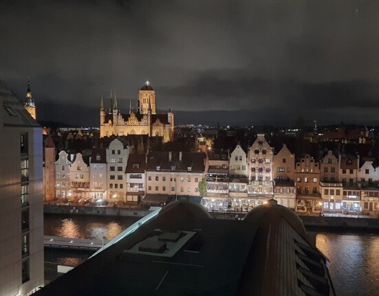 a city at night with a river and a castle