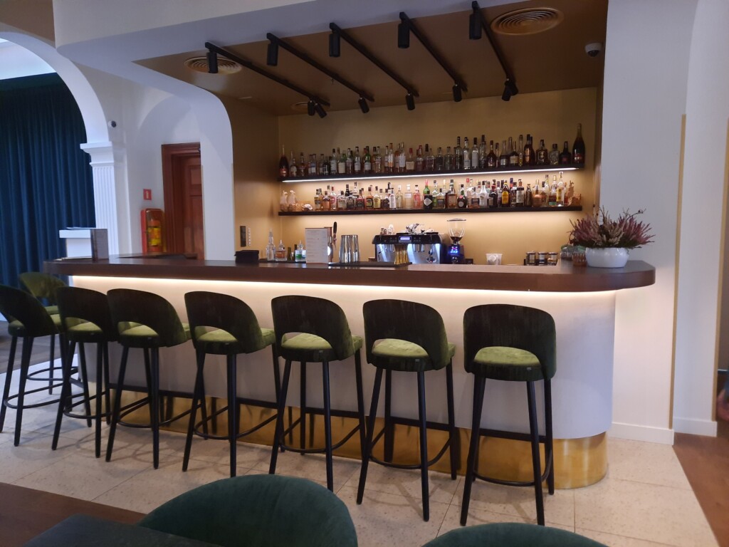 a bar with a row of chairs and a shelf with bottles
