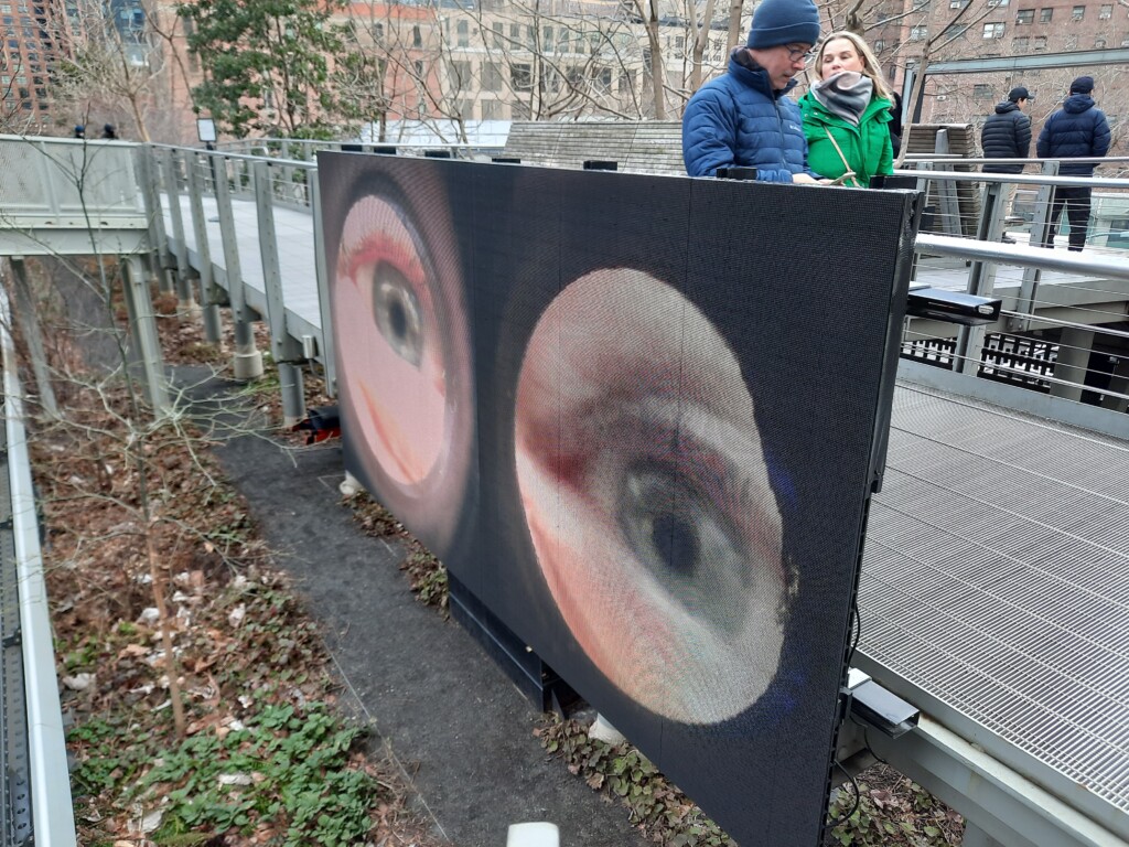 a man and woman standing next to a large screen with eyes