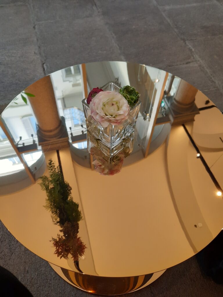 a glass vase with flowers on a round table