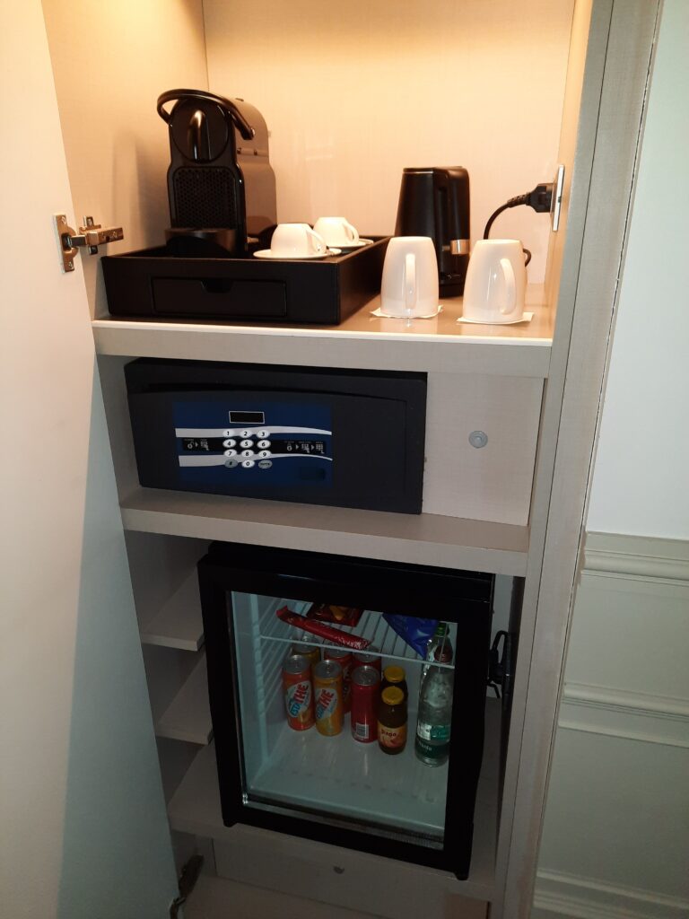 a small refrigerator with a small black box and coffee maker on top