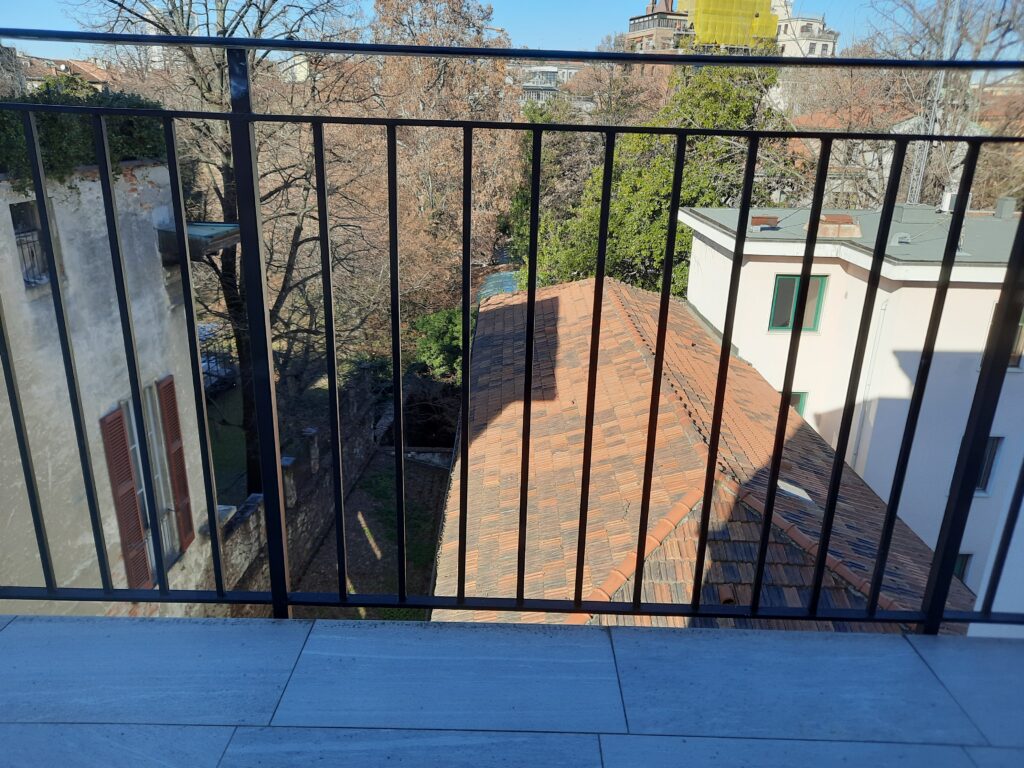 a balcony with a black railing and trees