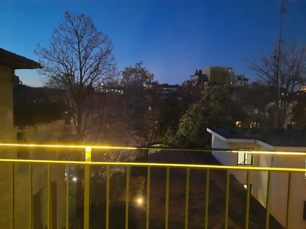 a yellow railing with trees and buildings in the background