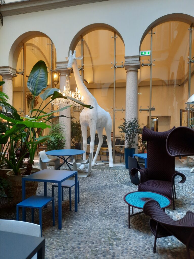a statue of a giraffe in a room with chairs and tables