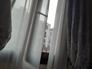 a window with curtains and a building in the background