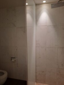a white tile wall with a light on the wall
