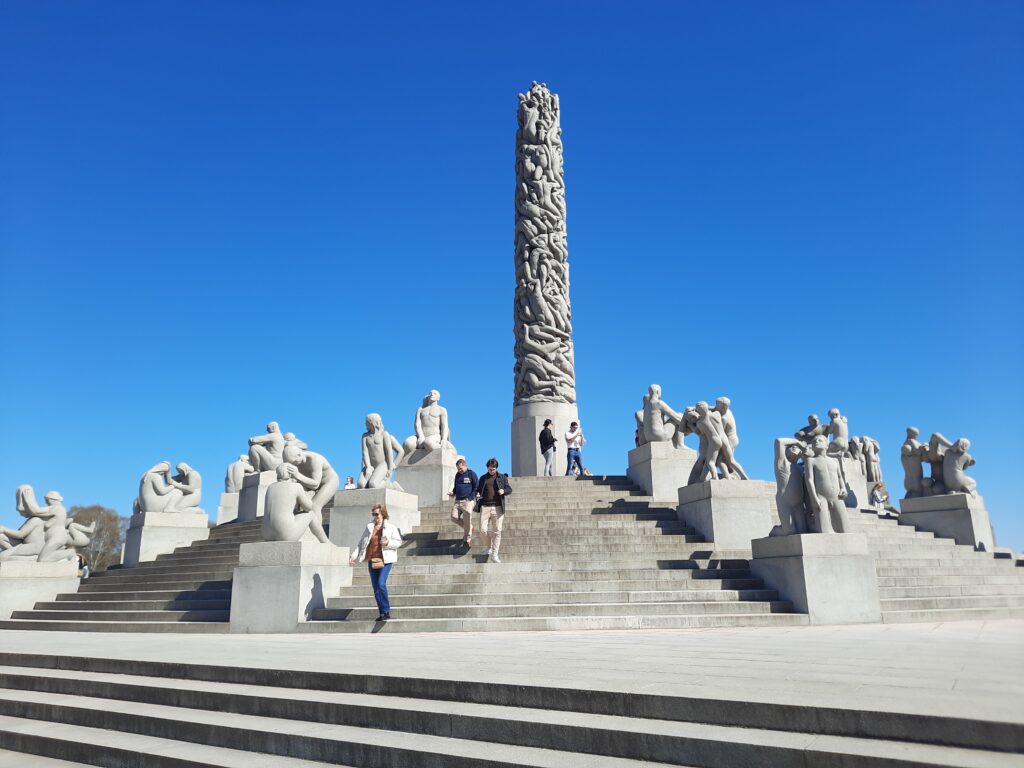 a group of people standing on stairs with statues on them with Frogner Park in the background