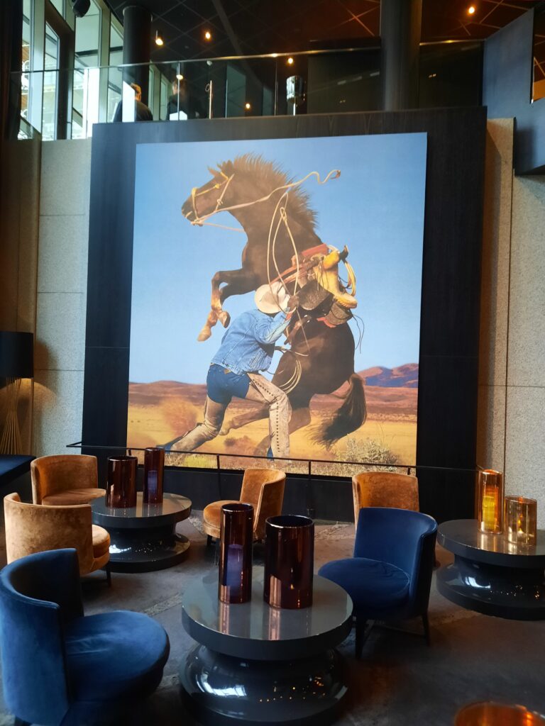 a large painting of a man riding a horse in a room with chairs