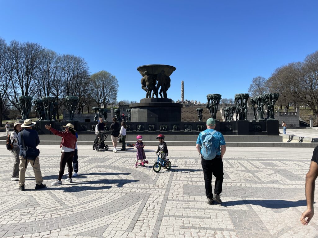 a group of people in a plaza with a statue of animals