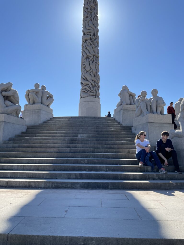 a group of people sitting on stairs in front of a statue